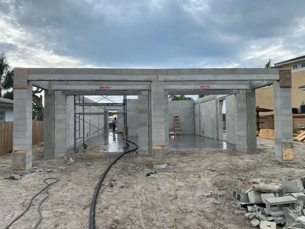 Elevated coastal home under construction in a Florida V zone, showing reinforced masonry columns and an open ground level below the elevated floor system