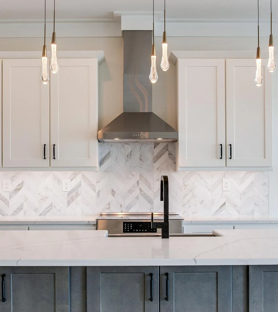 Kitchen range hood with a herringbone backsplash and white cabinets in a Seasafe elevated coastal home